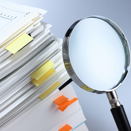 Investigate and analyze. Scanning business documents. Magnifying glass and stack of documents.